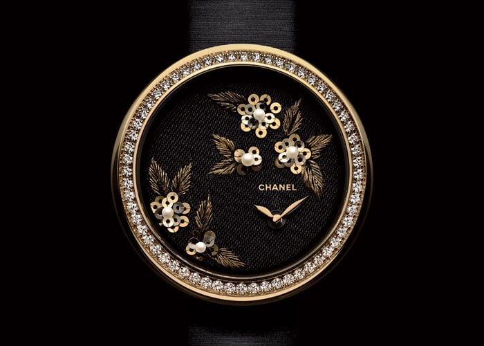 18K yellow gold and diamond case. Dial embroidered with camellias in gold and silk thread, natural pearls and gold spangles. High-precision quartz movement. Black satin bracelet with diamond-set ardillon buckle. Diameter: 37.5 mm. 