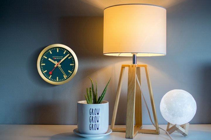 Mondaine – Mini Clock: Mondaine's station clock is a much-loved symbol of Switzerland. Now anyone can enjoy this icon of design, hung on a wall or set on a bedside table. Powered by a quartz movement, this Mini Clock (125mm in diameter) counts hours and minutes, with a luminous dot on the tip of each hand for easy read-off at night, and includes an alarm function. The dark blue dial is matched with a gold-coloured aluminium case. $