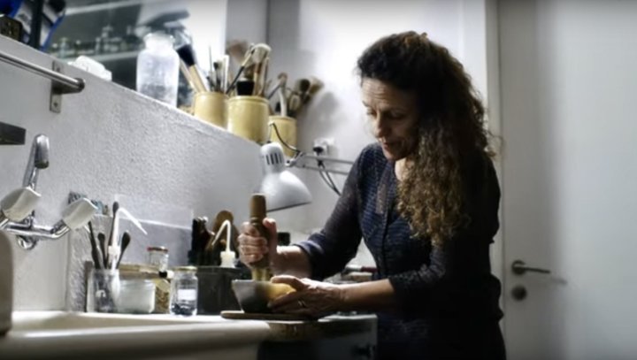 Anita Porchet prepares all her enamels by hand in her studio. She is seen here crushing coloured glass with a pestle to obtain sand-like particles which, combined with an aqueous solution, she will apply to the dial.