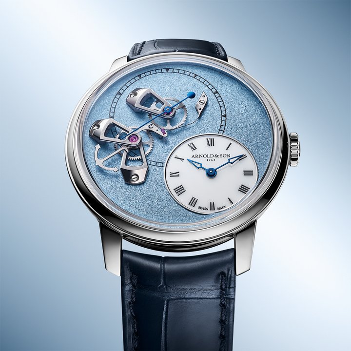The grained dials, with their dense texture and vibrant shine, are adorned with three openwork gold bridges supporting the true-beat seconds mechanism, facing the off-centred white opal hours dial. This subtle interplay of textures and finishes demonstrates the depth of complexity and singularity that defines the DSTB collection.