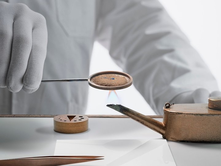 The single, open-tipped Breguet hand in steel is flame-blued and curved by an artisan.