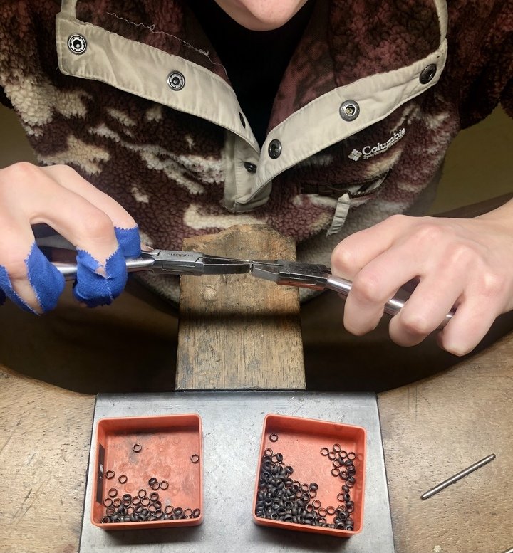 Sizing links. The endlessly repeated motion causes numerous blisters and sores, as evidenced by the blue protective tape wrapped around the fingers of the young chain maker working in Laurent Jolliet's workshop.