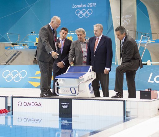 Omega Timing Chairman Peter Hürzeler, left, explains the swimming timing system to LOCOG Chairman Sebastian Coe, 2nd left, Swatch Group CEO Nick Hayek, 3rd left, International Olympic Committee President Jacques Rogge, 2nd right and Omega President Stephen Urquhart, right at the Aquatics Centre in London's Olympic Park 