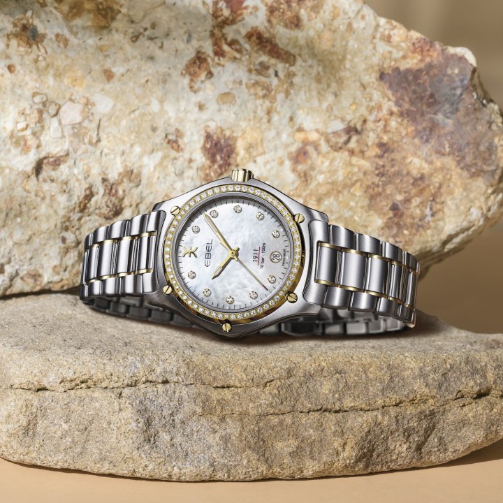 The Ebel 1911 Grande in 18k yellow gold and stainless steel has a mother-of-pearl dial with diamond hour-markers and a diamond-set bezel.
