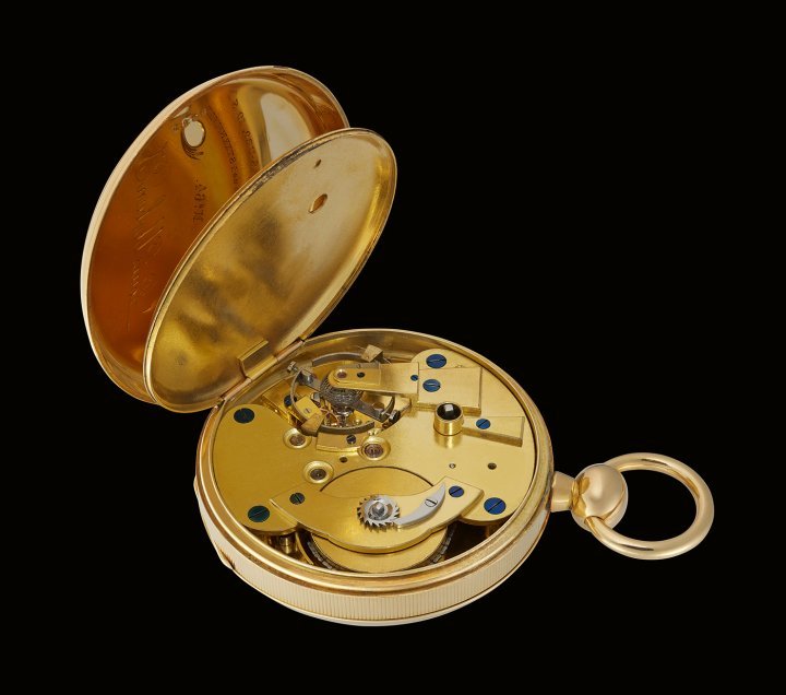Case: Heavy 18K gold case with fluted edge and smooth caseback. The inside of the caseback is stamped “2838”, “18 K” and “9”. Brass dust cover bears the following engraving: Chronometer-Gang, Compensations-Uro, 10 Steenhuller, 2 Steenlöftninger og 1 Steenhvilde, No 64, Louis Urban Jürgensen, Kiöbenhavn (Chronometer escapement, compensation balance, 10 jewels, 2 lifting jewels and 1 jewel rest). Small opening in the dust cover for winding the watch. Movement: 22.5 lignes movement with Earnshaw-type chronometer escapement. The ébauche was made by J. F. Houriet. Spherical balance spring in steel. Split temperature compensated balance with two wedge-shaped weights and two “time screws”. Ruby end stone. Dust pipe surrounding the winding square.