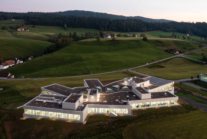 The new Les Saignoles site in Le Locle comprises 10,400 m2 of workshops spread over several split-levels that adapt to the topography of the site, and support the manufacturing flows. The building is equipped with large windows made of SageGlass, an electrochromic glass that changes colour according to the light. Two wood pellet furnaces and a heat pump eliminate the need to use fossil fuels for heating. 300 photovoltaic panels covering an area of 480 m2 are installed on the roof, providing 80 kW of energy output.