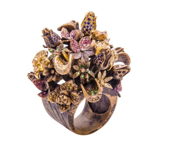 Le Bouquet Ring, a cocktail ring, designed in 18K yellow gold and rust-toned bronze, lending the piece a vintage appeal. The delicate flowers are set with white, brown, and yellow diamonds; blue, yellow, and pink sapphires, and green tsavorites.