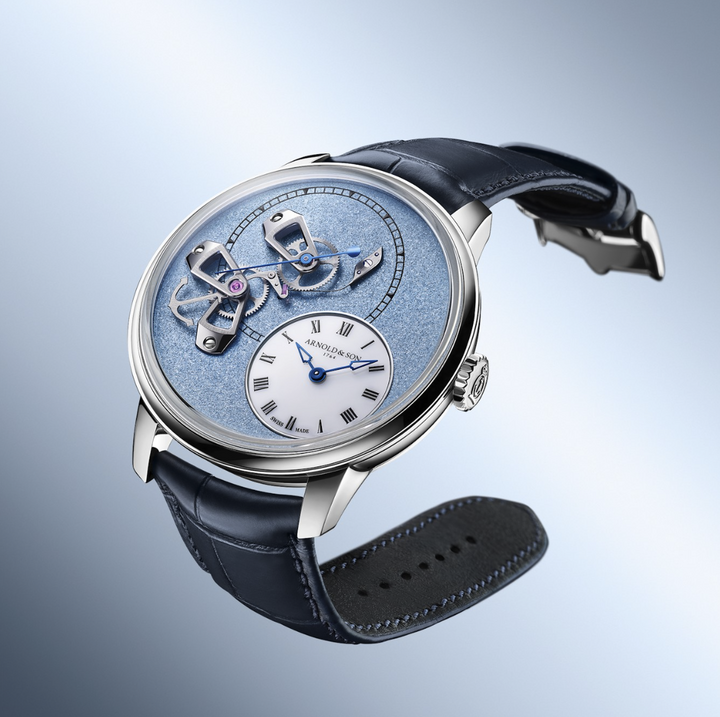 The grained dials of the DSTB 42 “Mint Green” (red gold) and “Ascot Blue” (platinum), with their dense texture alive with light, feature three openworked gold bridges supporting the true seconds (also known as deadbeat seconds), positioned opposite the off-centred white opal hour dial.