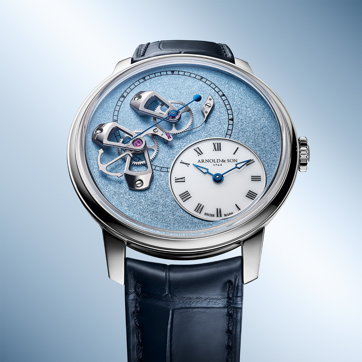 The grained dials, with their dense texture and vibrant shine, are adorned with three openwork gold bridges supporting the true-beat seconds mechanism, facing the off-centred white opal hours dial. This subtle interplay of textures and finishes demonstrates the depth of complexity and singularity that defines the DSTB collection.