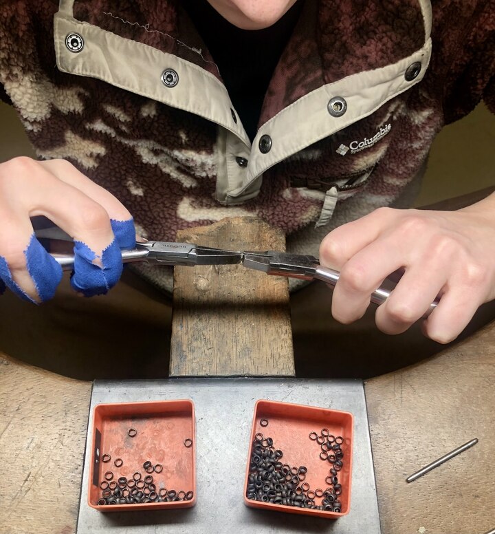 Sizing links. The endlessly repeated motion causes numerous blisters and sores, as evidenced by the blue protective tape wrapped around the fingers of the young chain maker working in Laurent Jolliet's workshop.