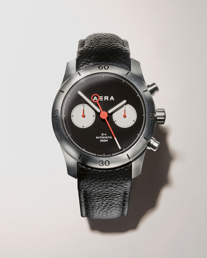 White counters and red lacquered hands punctuate the C-1 Chrono's matte black dial. The circular seconds-hand counterweight aligns with the C-1 signature and both As in the Aera logo as it sweeps.